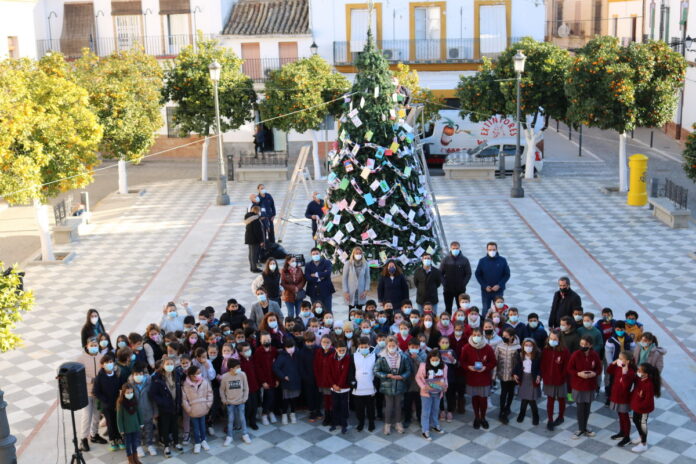 Alumnos de 4º de Primaria de Lora del Río decoran con sus tarjetas navideñas el gran árbol de Navidad que preside la Plaza de España